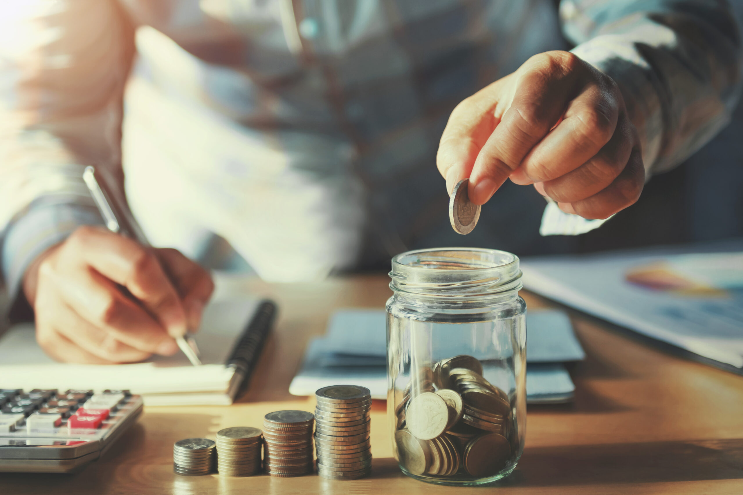 man at desk placing coins in jar